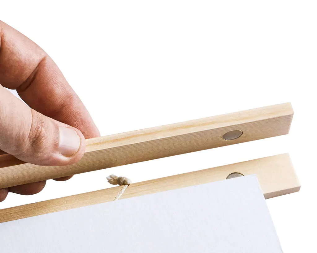 Hand öffnet Holzleiste mit Poster