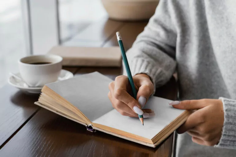Notizbücher selbst gestalten: 5 kreative DIY-Ideen Frau schreibt in ein Notizbuch und trinkt Kaffee